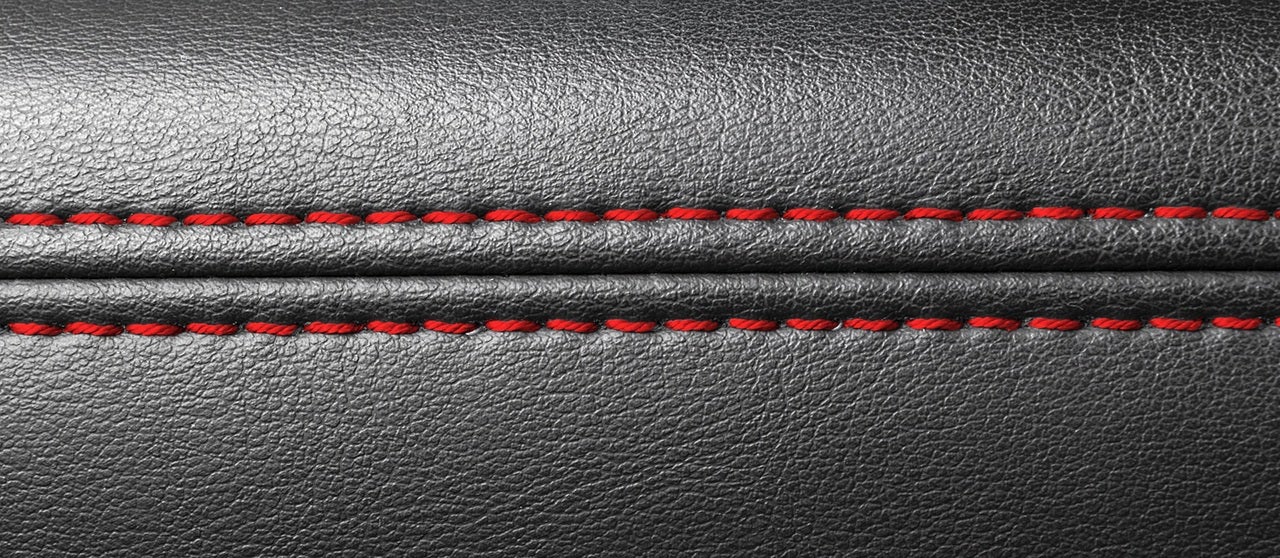 Modern sport car black leather interior. Part of leather car seat details with red stitching. Car detailing.