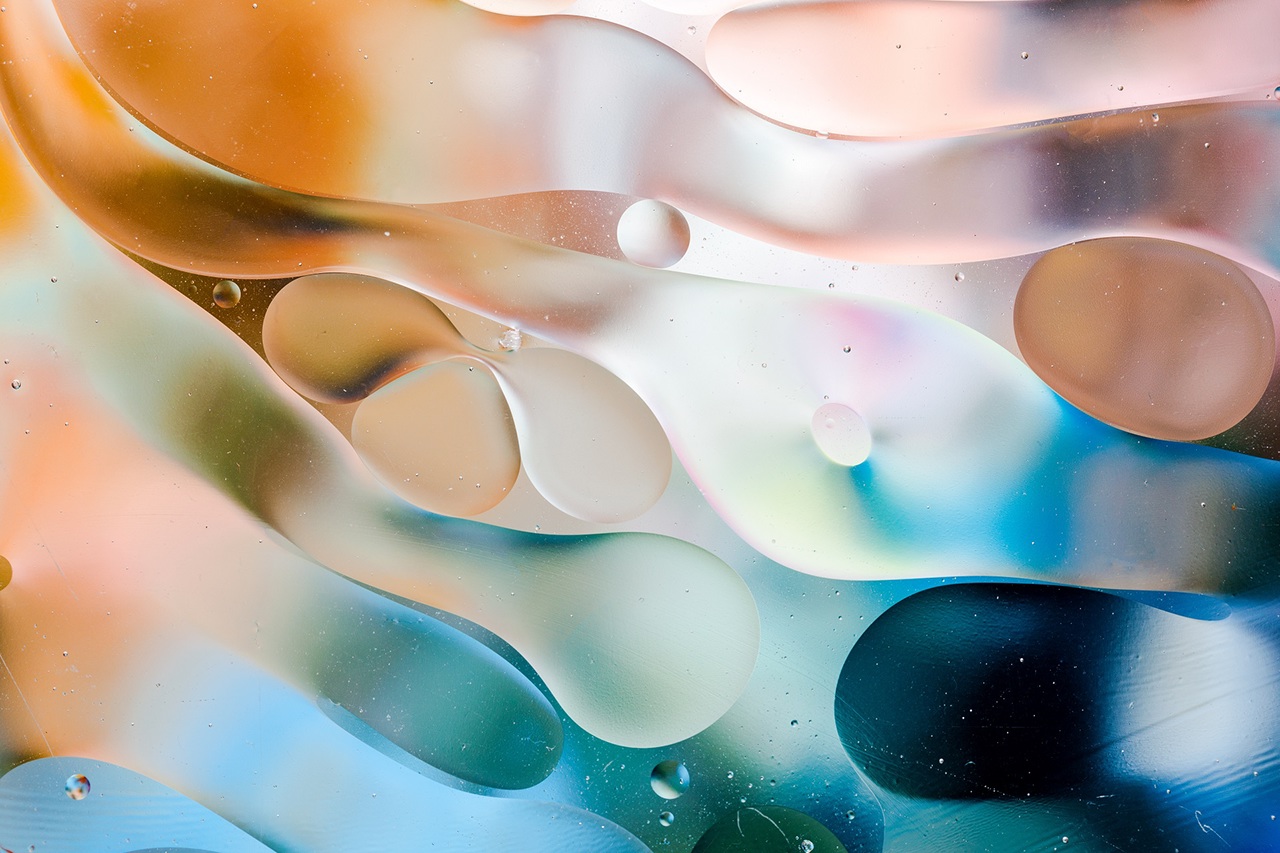 Close-up of the movement of oil droplets on the water surface. Colorful abstract macro background of oil drops on the water surface