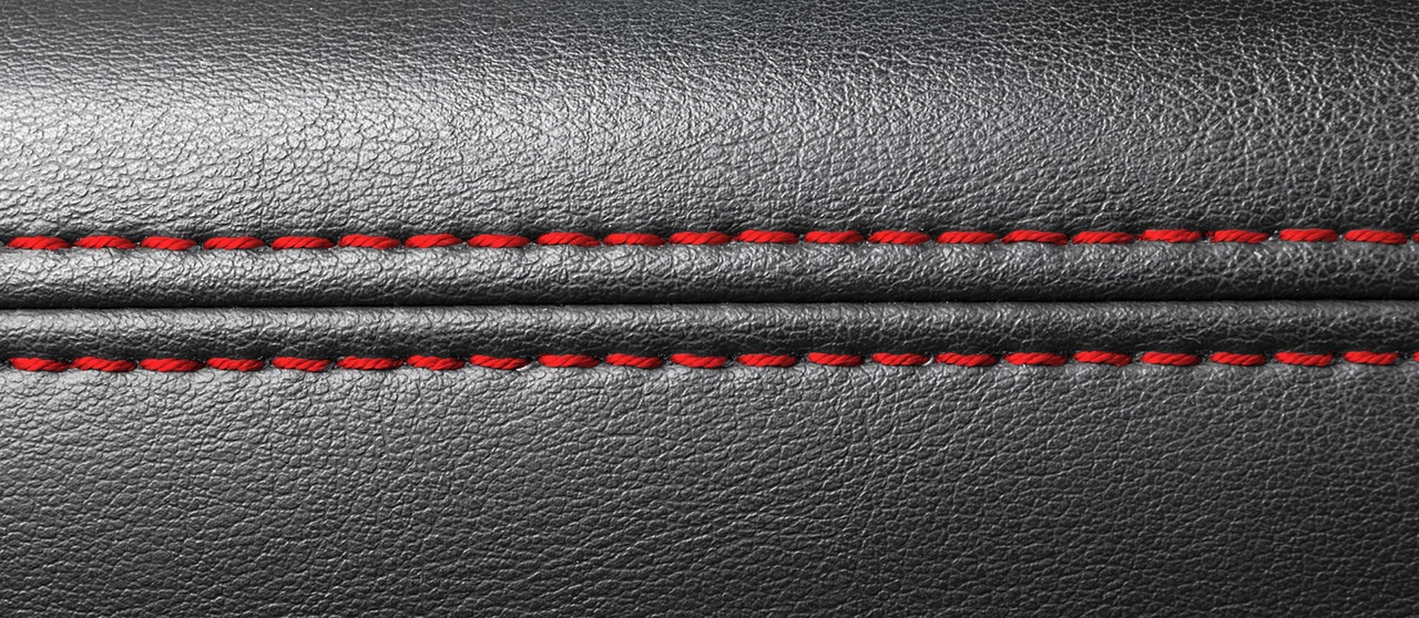 Modern sport car black leather interior. Part of leather car seat details with red stitching. Car detailing.