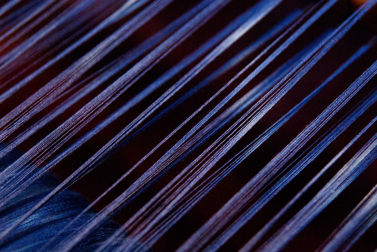 Detail of blue thread being woven at a loom