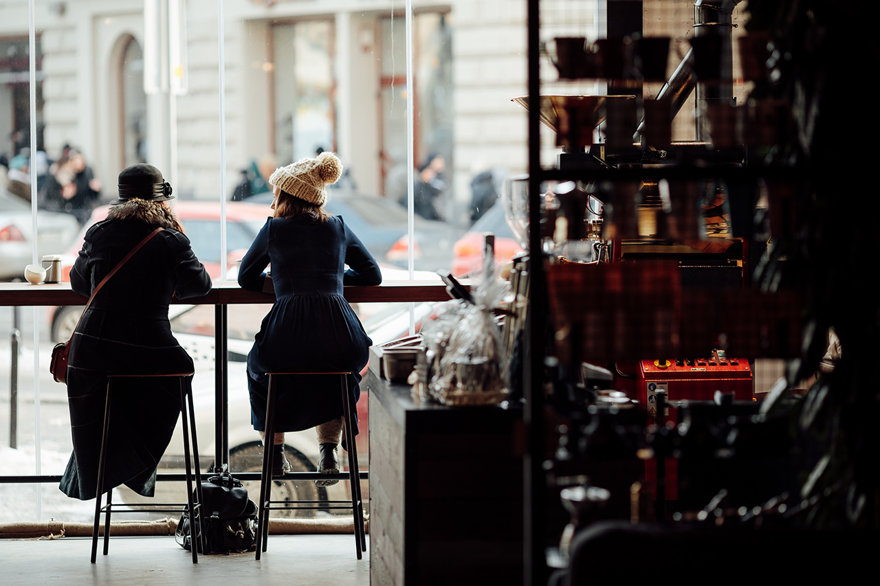 Two woman sit on the table at coffee place and talk to each other