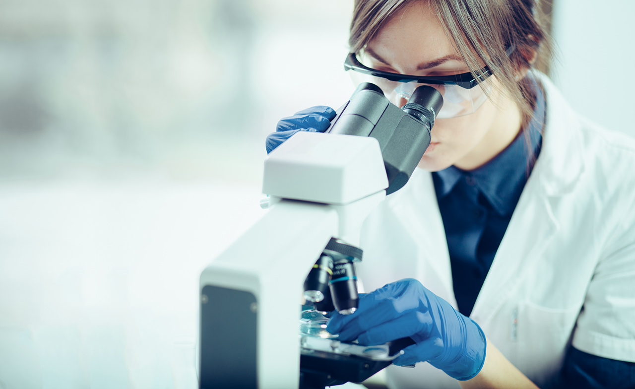 Young scientist looking through a microscope in a laboratory. Young scientist doing some research.