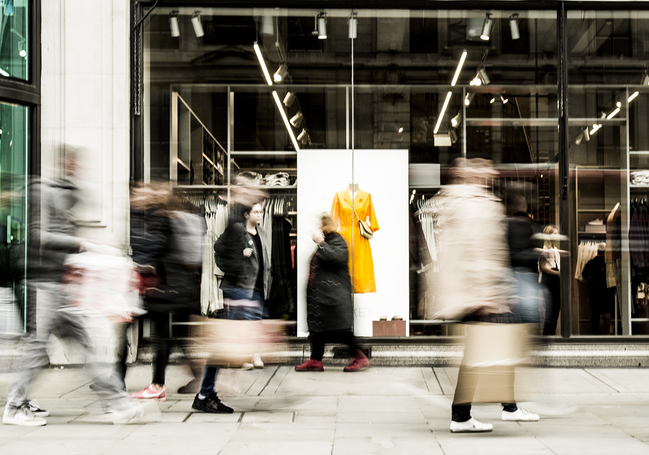 Motion blurred people walking past shop window