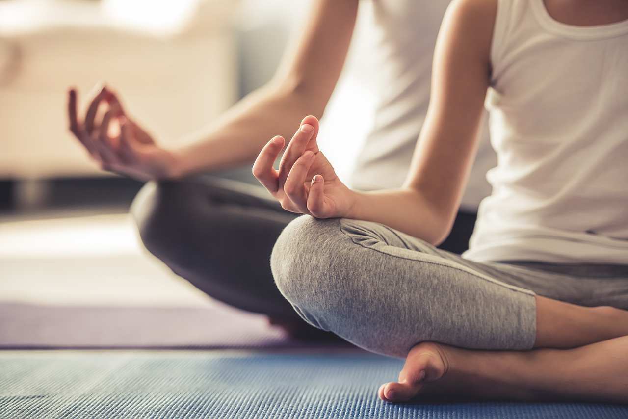 Cropped image of young woman and her little daughter doing yoga together at home