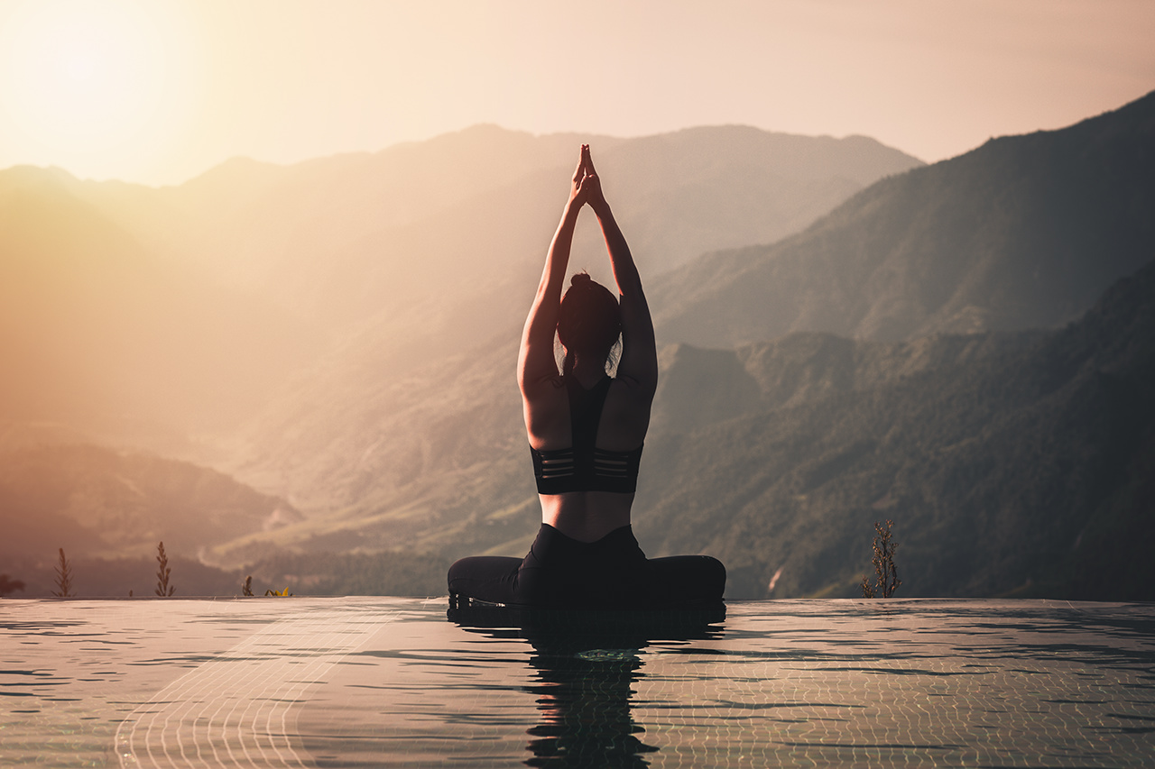 Beautiful Attractive Asian woman practice yoga Lotus pose on the pool above the Mountain peak in the morning in front of beautiful nature views,Feel so comfortable and relax in holiday,Warm tone