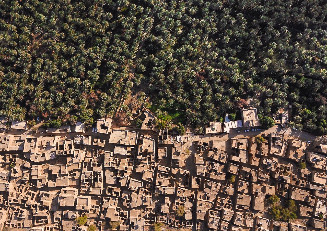 Aerial drone view of an old traditional Omani mud village in the mountains among date palm trees. Al Hamra, Oman.