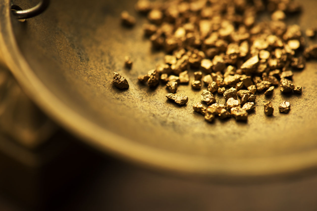 Trade and exchange. Weighing a gold nugget on a old brass scale dish.for trading. Shallow depth of field.