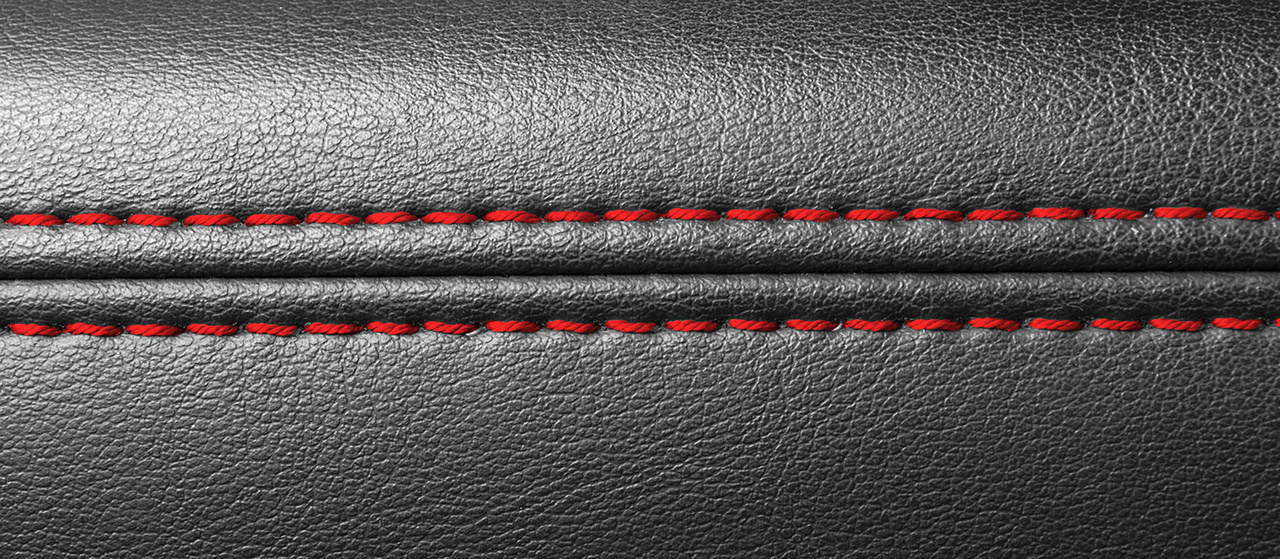 Modern sport car black leather interior. Part of leather car seat details with red stitching. Car detailing.