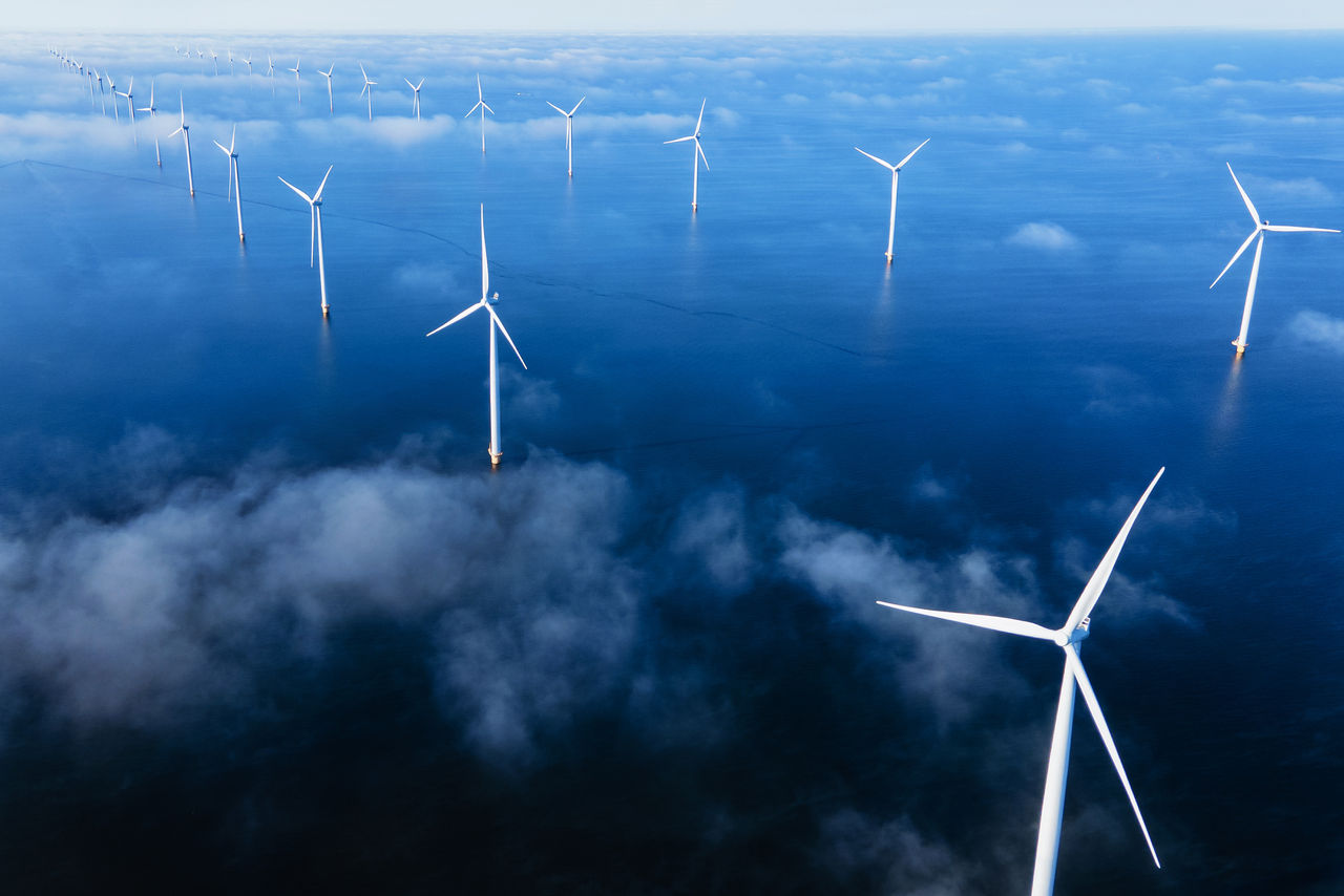 Aerial view at Windmill park with windmills turbines and a cloudy sky generating electricity with a blue sky green energy concept