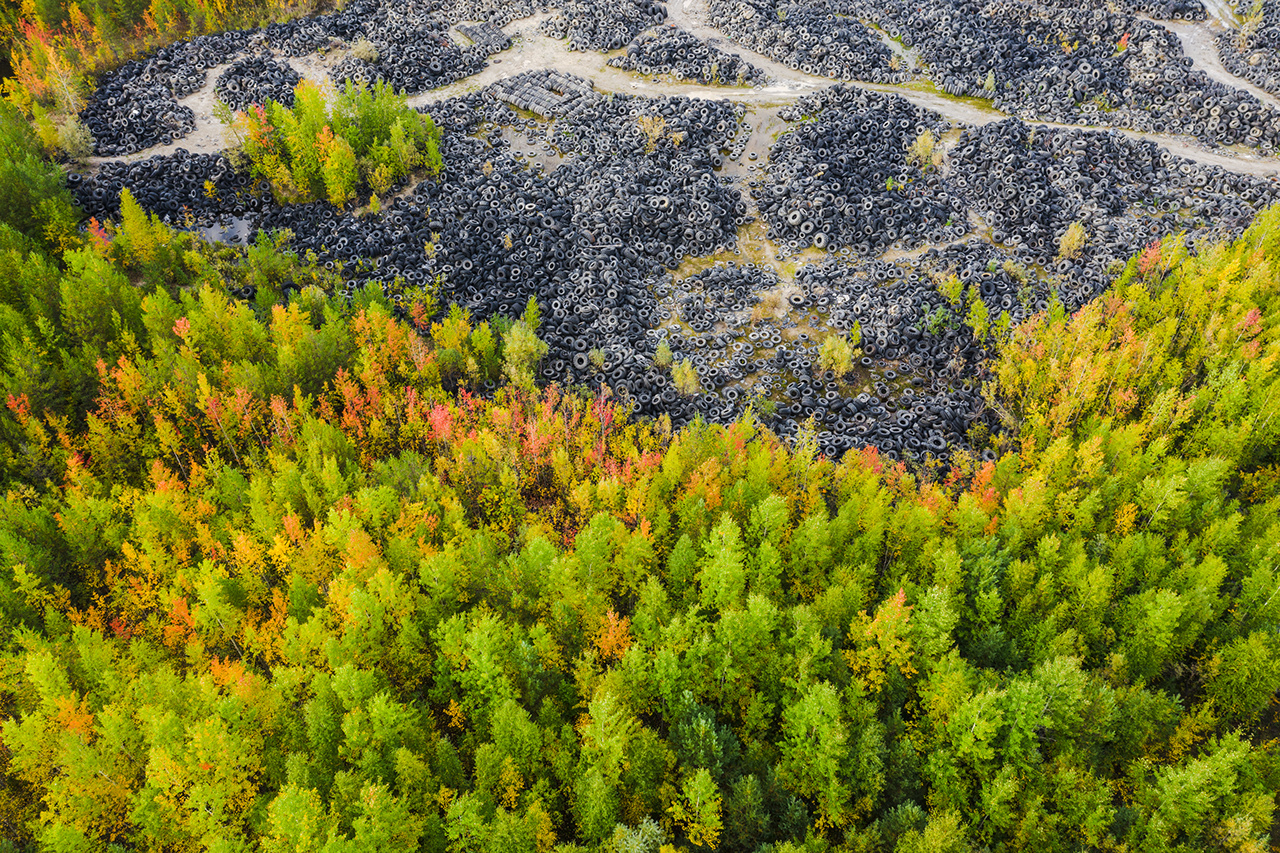 Top view on many car and truck tires on dump. Camera looking forward. Autumn forest.