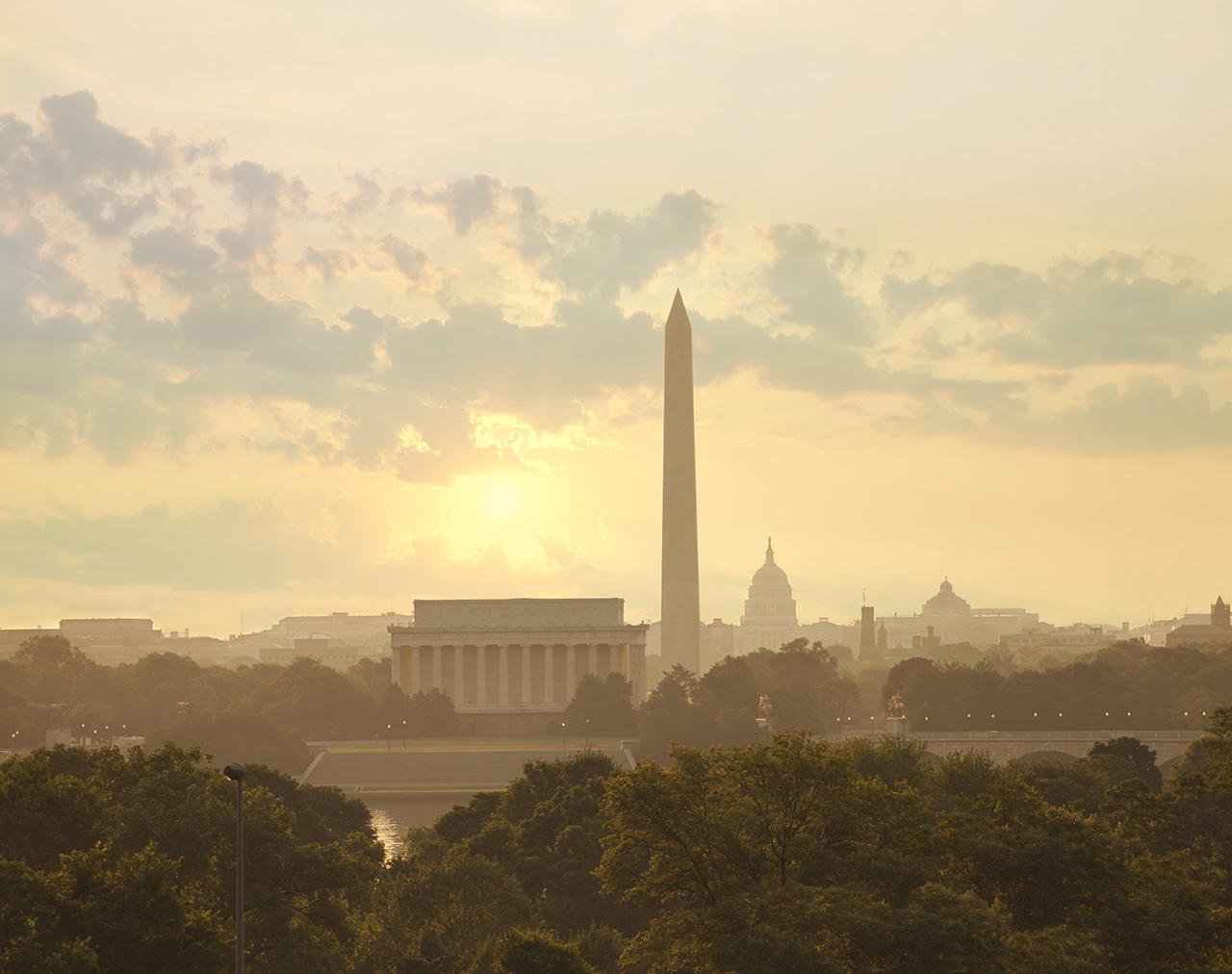 Washington DC skyline with sun and clouds in the morning showing the Lincoln Memorial, the Washington Monument and the Capitol