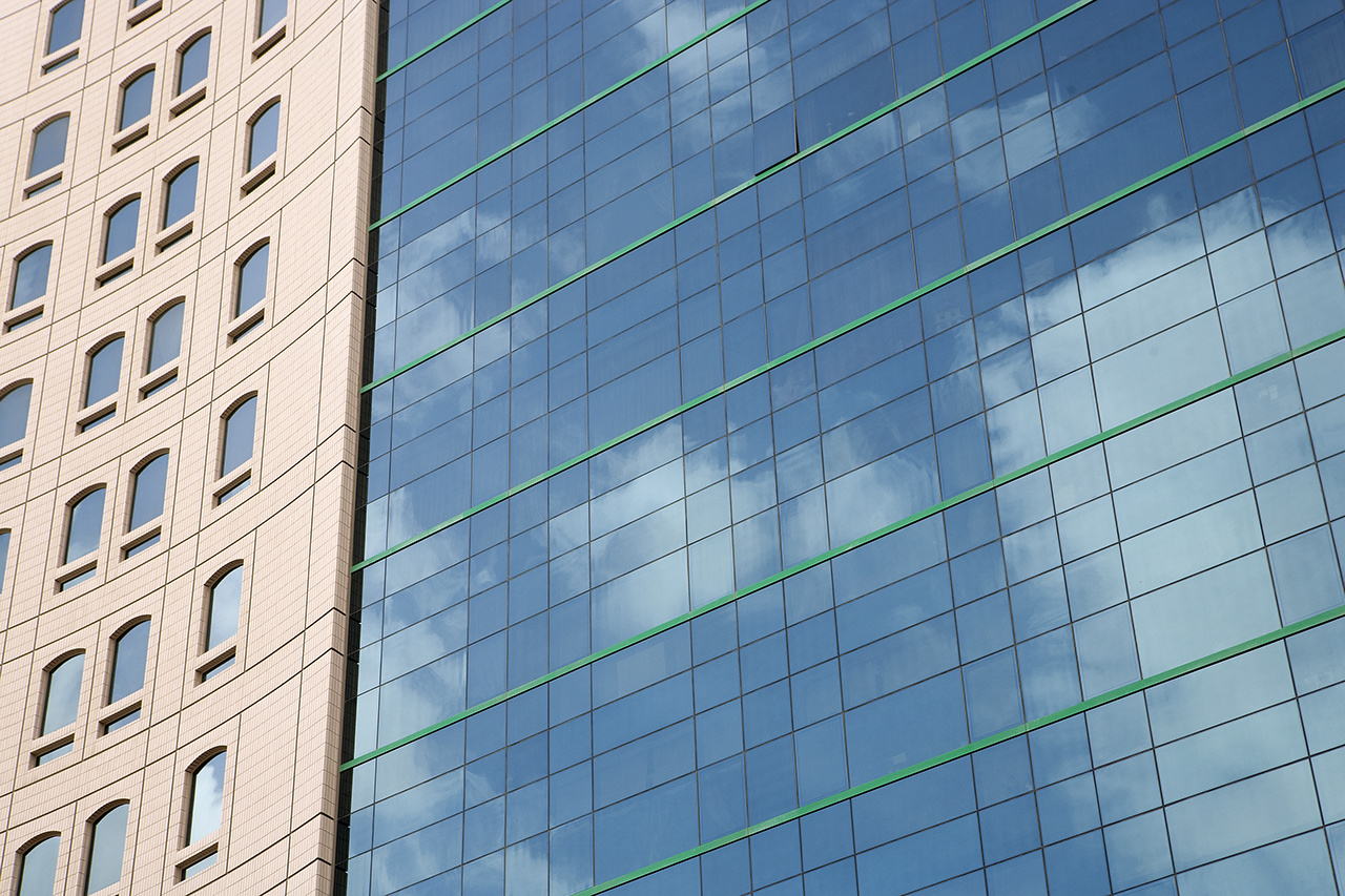 Modern office building with a reflection of blue sky in Dubai.