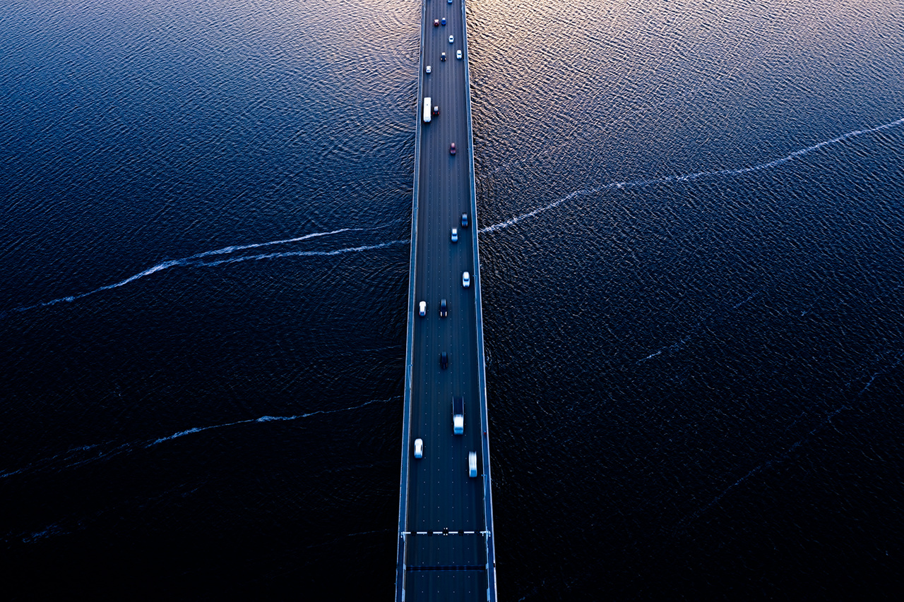 Aerial of Tasman bridge over wide flowing Derwent river in Tasmania Australia, with traffic, cars and trucks, crossing at sunset.